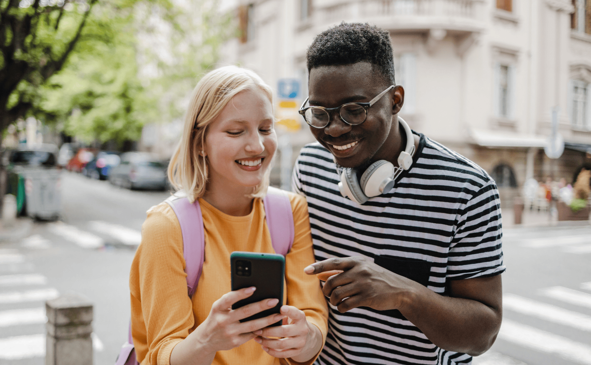 Young woman and man smiling while using a smartphone to bundle their cards.